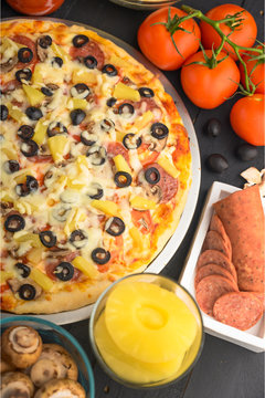 Italian pizza with ingredients on a dark background. Vertical photo.