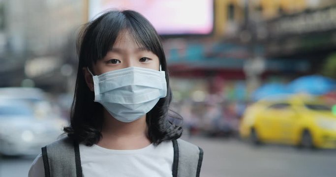 Little girl wearing mask and looking to camera at city. Health care and medical concept.