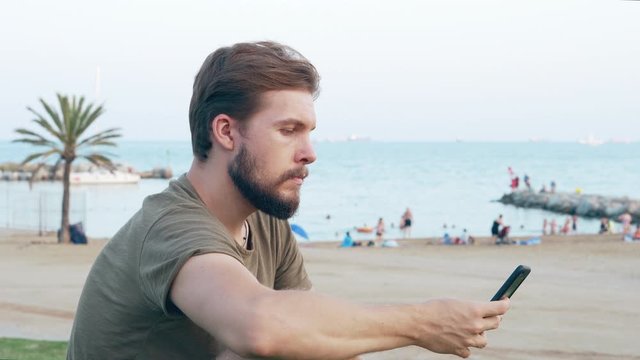 Young man on beach using smartphone