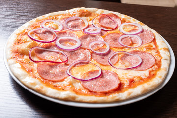 Inexpensive pizza, with pepperoni, onions, with tomato sauce.