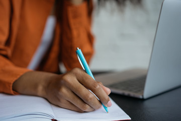 Woman writer using laptop computer, taking notes. Closeup shot of university student hand holding...