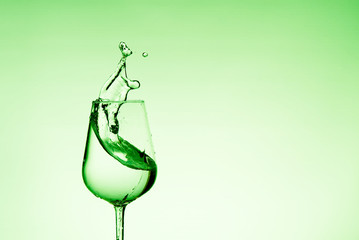 beautiful splashes of water in a wine glass, with green filter, close up with copy space.