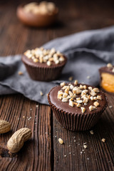 Cold crunchy treat, chocolate cups with caramel and peanut butter filling, sprinkled with chopped nuts