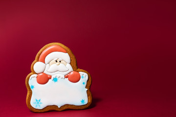 gingerbread cookie of Santa portrait with copyspace on red background. Traditional Christmas food. Christmas and New Year holiday concept.