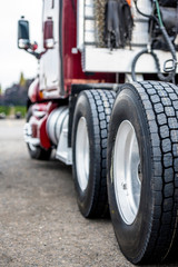 Wheels of big rig dark red semi truck with embossed tire tread