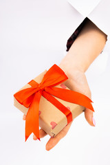 New Year's gift with a red ribbon in hands with manicure. Christmas. Paper Cut.