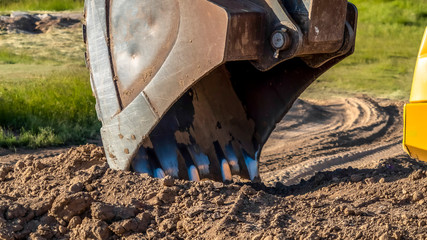 Panorama frame Focus on the bucket and arm of an excavator digging soil at a construction site