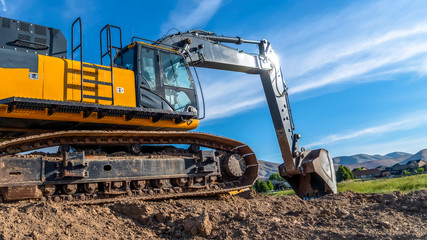 Obraz premium Panorama frame Yellow excavator with continuous tracks digging soil at a construction site