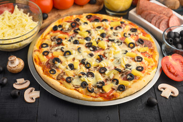 Pizza with ingredients, tomatoes, salami, mushrooms, mazzarella sauce and cheese and pizza knife. Italian pizza, culinary recipes concept, menu, restaurant, gourmet cuisine.