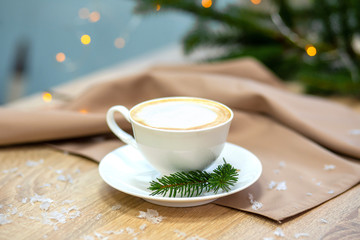 Delicious cappucino coffee cup . fireflies and spruce branches.