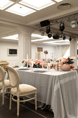 The white table in the restaurant is decorated with fresh flowers. Stylish event decor