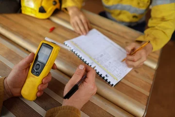 Fotobehang Construction miner hand holding checking at breathalyser breath alcohol testing equipment while his friend writing zero alcohol in the blood system on the daily sheet prior to work on mite site © Kings Access