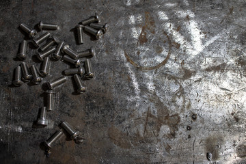 Screws and bolts lie on a metal table.