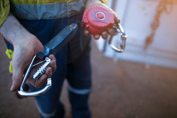 Male inspector hand testing opening locking carabiner gate which connecting with self retracting...