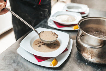 The cook pouring soup into plate.