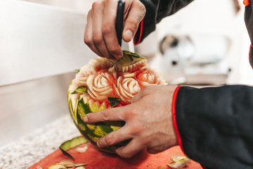 Obraz premium Professional chef in kitchen restaurant carving watermelon.
