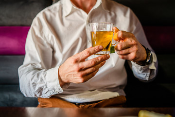 Midsection of man wearing white shirt holding a glass cup of tea