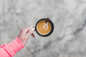 woman's hand holding coffee cup with latte from topdown perspective
