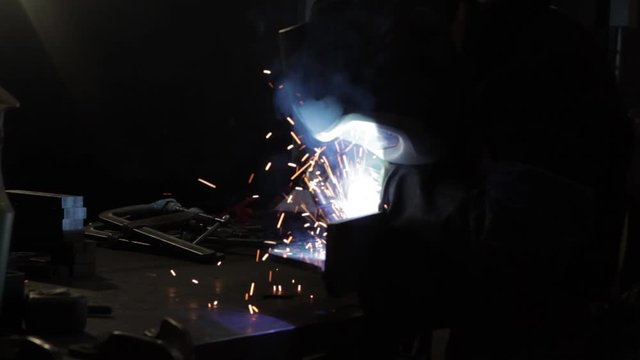 Person welding in a dark factory