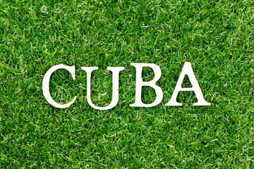 Wood letter in word Cuba on green grass background