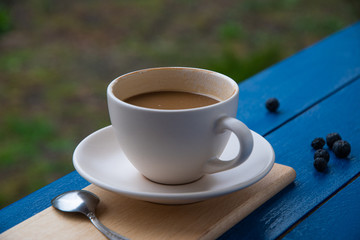 A cup of coffee with milk on a table in the garden.