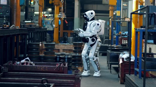A cyborg with a tablet checks factory equipment.