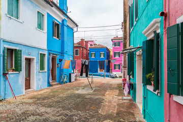 Fototapeta na wymiar Burano, Venice, Italy - May 21, 2019: Colorful painted residential houses in Burano island, Venice, Italy. Burano street with ?olorful facade building. Colorful architecture in Burano island.