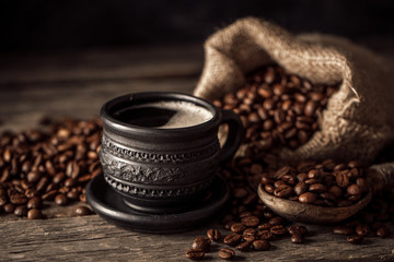 Coffee cup with coffee beans on wood background.