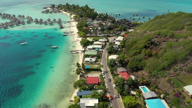 Aerial of a beautiful tropical island with charming overwater bungalows, drone flying forward along the coast - Bora Bora, French Polynesia