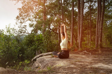 Young beautiful Asian woman practices yoga and meditates outdoor in the forest. Female doing yoga and meditate to relax and release stress. Weight Loss. Health care and lifestyle.