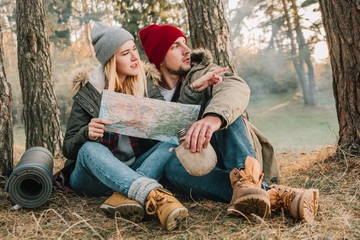 Travel couple camping with map in the forest. Concept of trekking, adventure and seasonal vacation.
