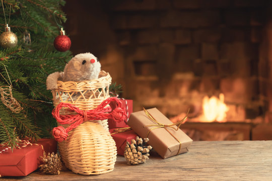 Christmas composition - mouse is symbol of 2020 according to Chinese horoscope in wicker boot under Christmas tree in room by fireplace