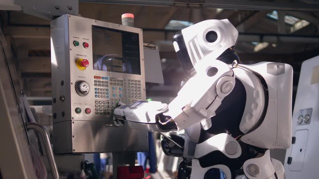 White cyborg works with a tablet, checking factory machine.