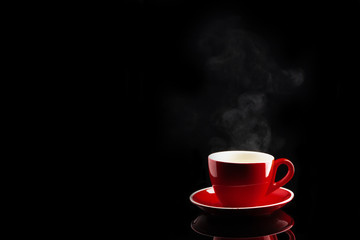 steaming coffee or tea in red cup with reflection on dark background