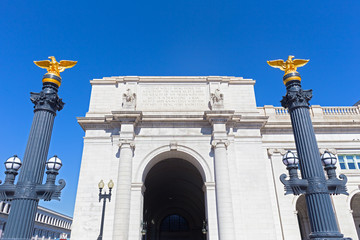 Decorative columns with eagle statues on top in front of the Union Station in Washington DC, USA. Left wing of the Union Station in US capital city under blue skies.