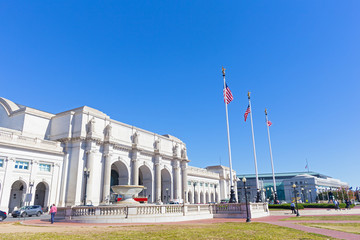 A square in front of the Union Station Building in Washington DC, USA. Facade of the Union Station Building with marble statues on top of columns on a sunny afternoon.