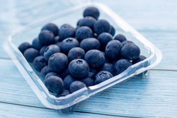 A tray of delicious fresh superfood blueberries on a wooden background