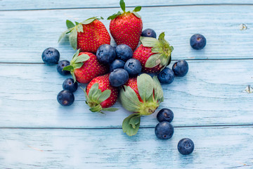Naklejka na ściany i meble Blueberries and strawberries on a wooden background. Summer healthy lifestyle concept