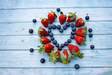 Naklejka na ściany i meble Blueberry and strawberry heart on a wooden background. Valentines day concept