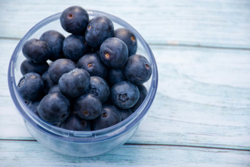 Superfood berries: blueberries in a bowl on a wooden background.
