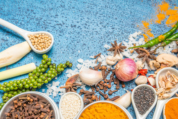Variety of spices and herbs in a cup and spoon on a wooden background.