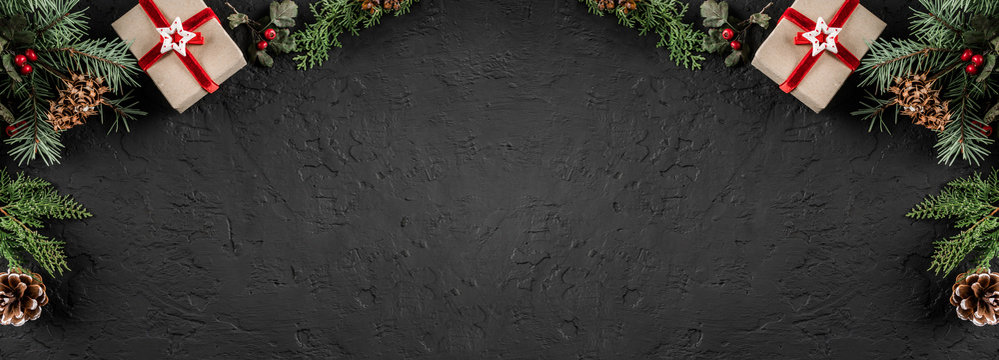 Creative layout frame made of Christmas fir branches, pine cones, gifts on dark background. Xmas and New Year theme. Flat lay, top view, wide composition