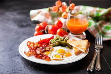 breakfast - fried eggs, haricot, a paprika and bacon in a plate, selective focus
