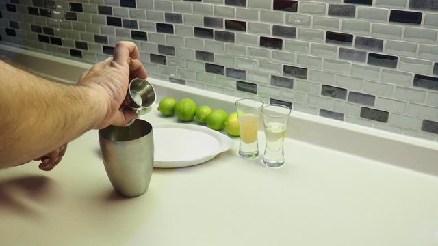 margarita cocktail preparation. The bartender prepares margarita cocktail by mixing tequila, orange liqueur and lime (lemon juice). Salt is served on the edge of the glass
