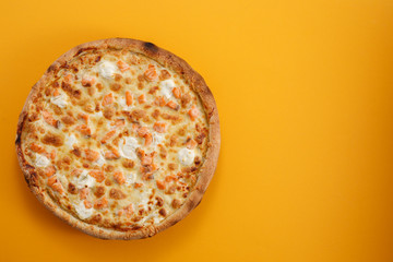 Pizza with salmon and cheese on a yellow background. Closeup. The concept of delicious food. View from above.