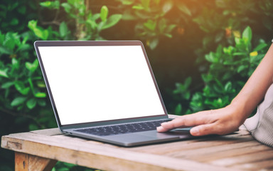 Mockup image of a woman using and touching on laptop touchpad with blank white desktop screen on wooden table