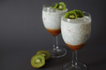 Healthy chia pudding in a glass with fresh kiwi and strawberries jam