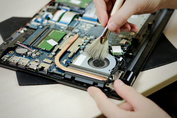 Naklejka premium Cleaning the laptop from dust with a brush. Close up