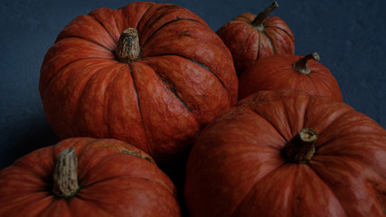 Orange pumpkins close-up, top view, selective focus. Template fall harvest thanksgiving halloween anniversary invitation cards. Dark background, photo in dark processing