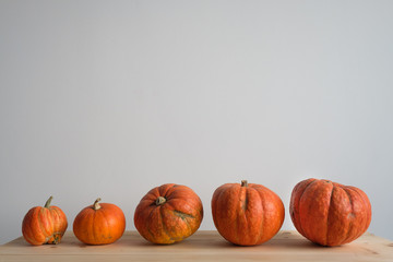 Halloween and Thanksgiving. Autumn concept. 5 orange pumpkins of different sizes on a wooden table....